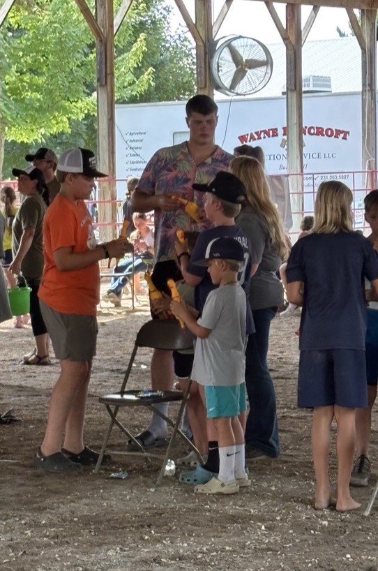 A young man talking to other youth in a covered pavilion.
